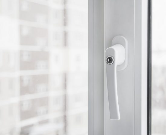 White secure UPVC window with lockable handle. Closeup, selective focus